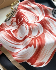 Close-up of orange floral silk scarf with premium twill texture and khaki hem detail