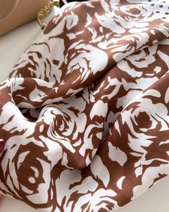Detailed close-up of brown floral camellia print scarf with polka dots and silk-like texture