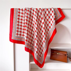Dettaglio di un foulard in seta con motivi geometrici rossi e bordo a spirale nero