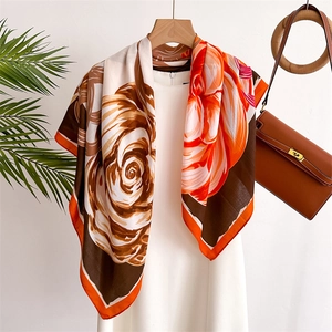 Detailed close-up of a floral silk square scarf in orange and brown with elegant draping