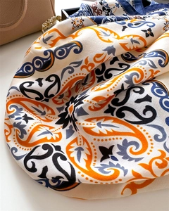 Detailed view of paisley silk scarf texture with floral pattern and leather handbag