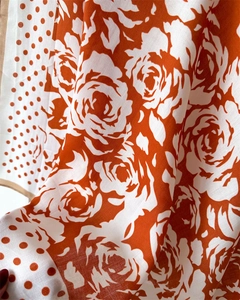 Close-up of orange silk scarf showing large white camellia print and dot border texture