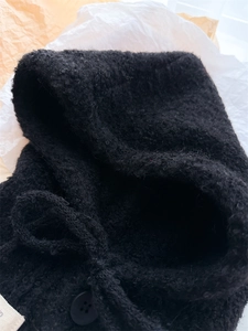 Dettaglio della maglia in lana bouclé nera con bottone e chiusura con coulisse