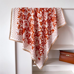 Detail of silk-feel floral scarf with orange rose patterns and polka dots on a white base