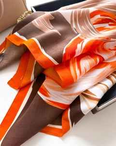 Detail of elegant silk scarf featuring orange and brown geometric patterns on twill fabric