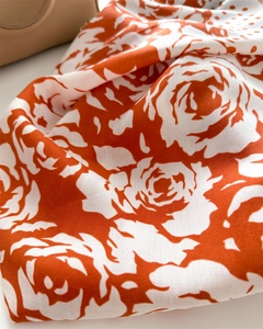 Close-up of orange and white floral silk scarf with rose print and herringbone texture