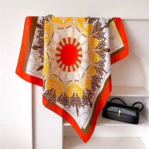 Detail eines eleganten orangefarbenen Seidenschals mit Barockmustern auf einem Ständer