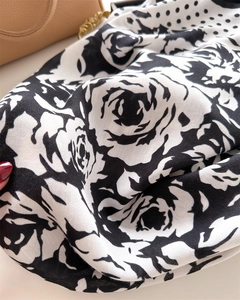 Macro view of silk scarf fabric showing classic camellia print and herringbone texture