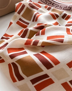 Macro detail of silk-like scarf with geometric patterns in orange and brown tones