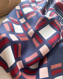 Close-up of a 90cm silk-like scarf with geometric patterns and herringbone weave texture