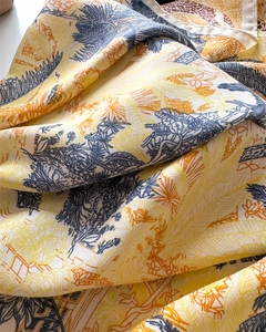 Close-up of tropical palm and floral print on soft silk-like fabric scarf with rolled edges