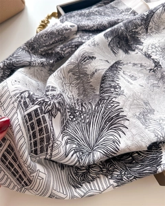 Detailed view of monochrome landscape print on soft silk-like fabric scarf with fringes