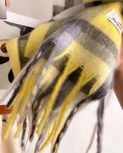Dettaglio di sciarpa a quadri gialli e grigi con frange morbide e trama in maglia