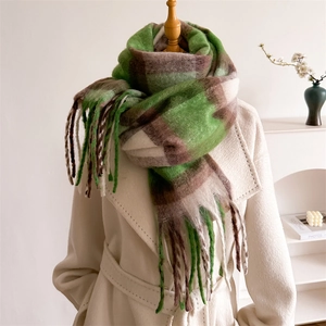 Dettaglio della sciarpa spessa a quadri verdi e marroni con frange su cappotto beige