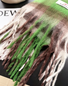 Dettaglio della trama della sciarpa a quadri verde e marrone con lunghe nappe