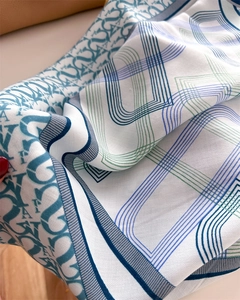 Macro detail of silk scarf showing twill texture and geometric letter patterns in green and blue