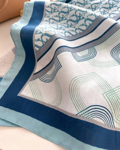 Close-up of silk scarf with blue geometric monogram prints and fine twill texture