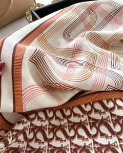 Close-up of silk scarf showing V-pattern monogram and geometric print on fabric