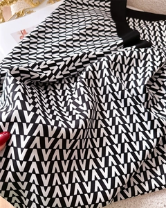 Macro detail of silk scarf featuring classic black and white repeating V-pattern texture