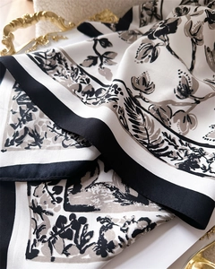 Detailaufnahme eines Seidenschals mit Blumenmuster auf einem eleganten Goldtablett