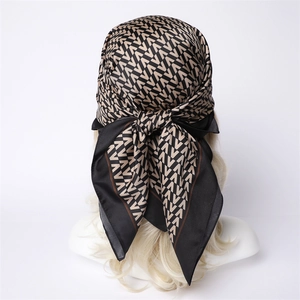 Close-up of geometric V-pattern silk scarf tied on a blonde mannequin head in black and gold
