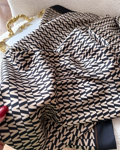 Detail of satin scarf with repeating V-pattern and elegant gold handle tray