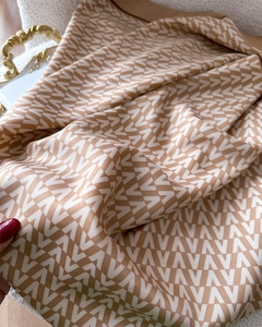 Detailed view of luxury satin scarf featuring golden V-shaped geometric patterns