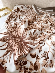 Detailansicht der Vintage-Blumenmuster-Seidenschal-Textur auf weißem Lammfell-Stuhl