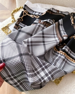 Detailed view of silk scarf with houndstooth pattern and equestrian horsebit prints