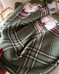 Detail of green silk scarf with vintage plaid and gold chain patterns on satin fabric