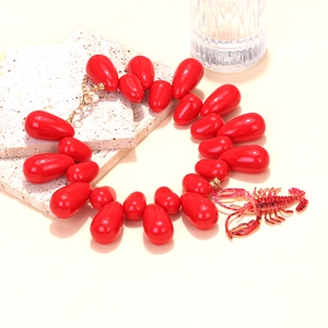Macro detail of red teardrop beads and realistic lobster pendant on summer necklace