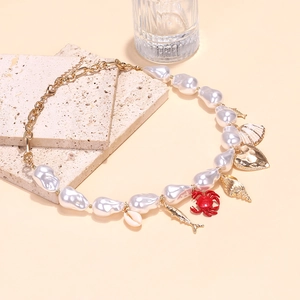 Baroque pearl necklace with gold ocean charms, shell, and crab on travertine stone