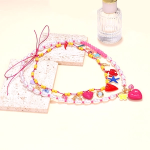 Detail of layered beaded necklace featuring colorful heart, starfish and crab charms