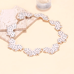 Handmade enamel leaf necklace with black polka dots on white petals and gold chain