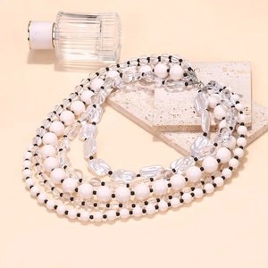 Detail of multi-layer beaded necklace featuring white and transparent beads with silver clasp