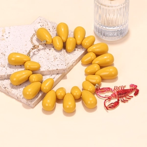 Macro detail of red crayfish pendant and yellow teardrop beads on ocean style necklace