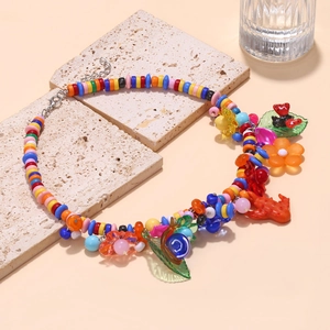 Close-up of colorful beaded necklace with flower and snail charms on a stone plate