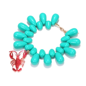 Detail of teal teardrop beads and a realistic red crayfish pendant with gold chain