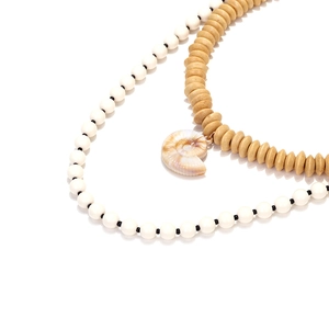 Bohemian layered wooden bead necklace with shell pendant on a white reflective background