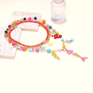 Gros plan détaillé du collier de perles bohème à plusieurs rangs avec charms de poissons tropicaux