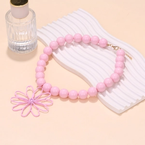 Close-up of pink handmade beaded necklace featuring a large hollow flower pendant and gold clasp