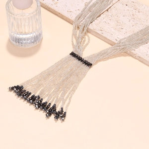 Macro detail of multi-strand white seed bead necklace with contrasting black crystal accents