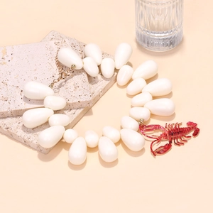 Detail of white water-drop bead necklace featuring a vibrant red lobster pendant