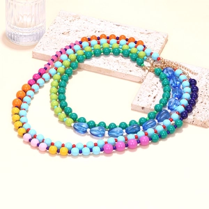 Macro detail of multi-colored beaded necklace with teardrop charms and golden lobster clasp