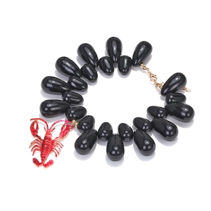 Macro view of black teardrop beads necklace featuring a detailed red crayfish pendant