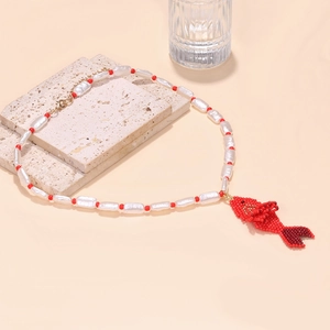 Detail of handmade beaded tropical fish pendant with white pearls and red accent beads