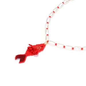 Macro detail of hand-beaded red tropical fish pendant with baroque pearl necklace chain