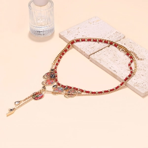Detail van gelaagde gouden en rode kralenketting met kleurrijke schedel hangers