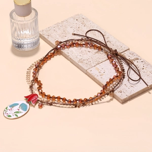 Detail of beaded necklace with colorful enamel floral pendant and amber crystal beads