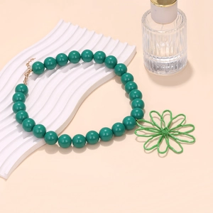 Detail of beaded necklace featuring a large green hollow floral pendant and adjustable chain